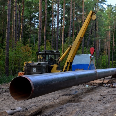 Pipelaying crane lowers a section of pipe into a trench. Construction of gas pipeline to new LNG plant. Crawler bulldozer with side boom operation install natural gas pipeline and oil pipes